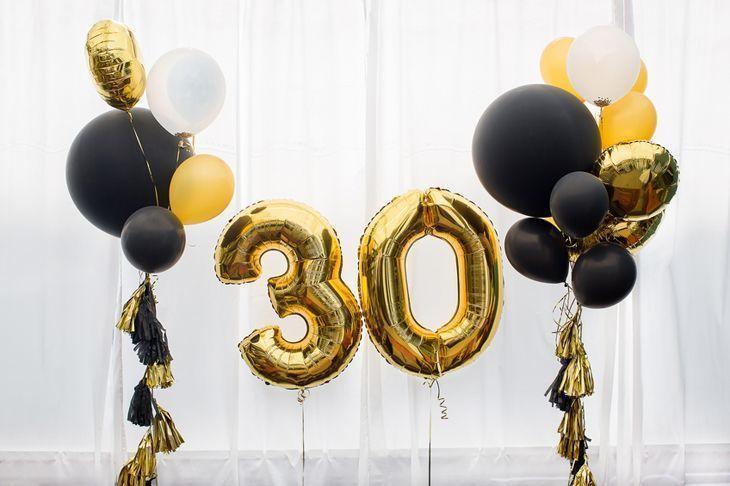 Decoration for birthday, anniversary, celebration of the thirtieth anniversary, white background, gold and black balloons with tassels