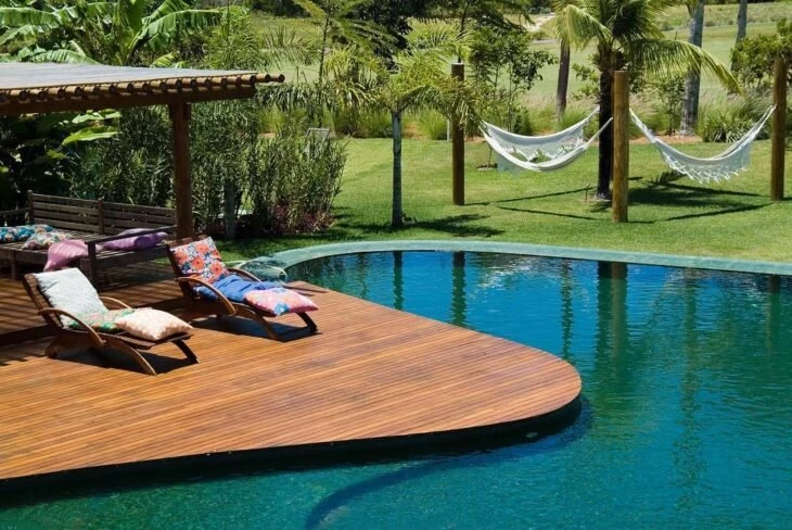 Deck para acompanhar uma piscina com curvas na área de lazer